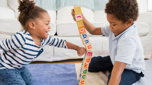 Black children playing with blocks in living room